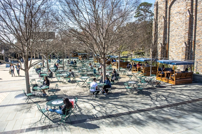 Photo of The Plaza with a closer view of people sitting at tables, chairs, and benches