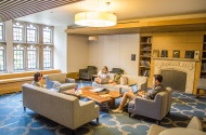 Photo of Brodhead Center Chaplin Family Study Room showing couches, armchairs, coffee table, windows, and three people studying